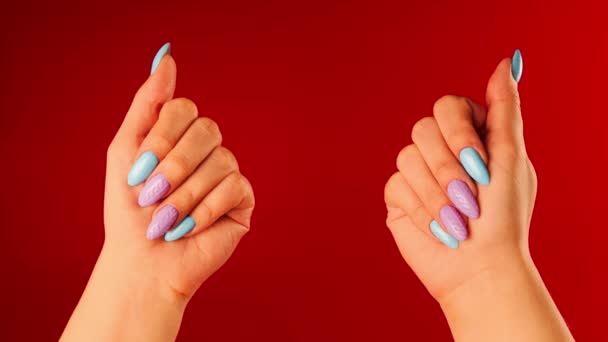 Vrouwen handen met mooie nagels op rode achtergrond. Onherkenbaar persoon toont manicure. Sluit maar af. Concept van zorg en schoonheid. — Stockvideo