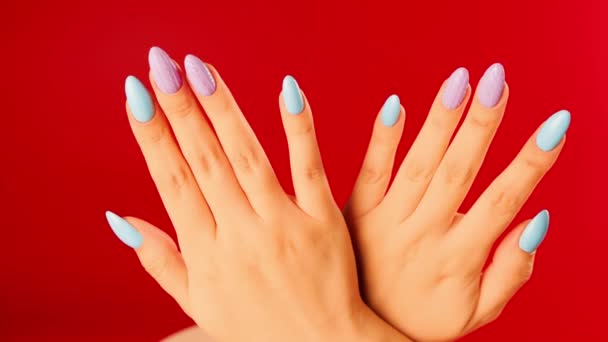 Mujeres manos con hermosas uñas sobre fondo rojo. La persona irreconocible muestra la manicura. De cerca. Concepto de cuidado y belleza. — Vídeos de Stock