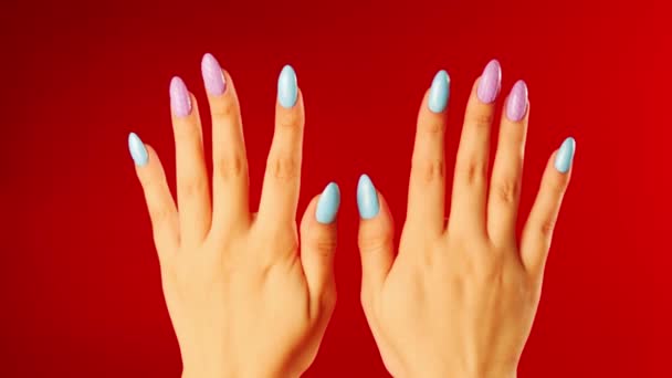 Mujeres manos con hermosas uñas sobre fondo rojo. La persona irreconocible muestra la manicura. De cerca. Concepto de cuidado y belleza. — Vídeos de Stock