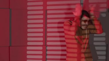 Karanlık odada, düşen kırmızı ışık ve gölge panjurlarıyla duvarın yanında duran gözlüklü genç, duygusal bir adam. Öfkeli erkek kafasını vurur, küfreder, el sallar, şok halinde facepalm yapar..