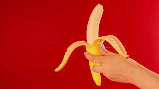Mano Mujer Sostiene Plátano Semi Pelado Sobre Fondo Rojo Persona — Vídeos de Stock