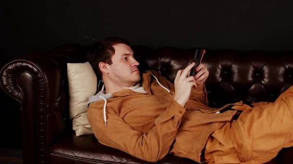 Homme Naviguant Smartphone Sur Canapé Focalisé Mâle Vêtements Décontractés Messagerie — Photo