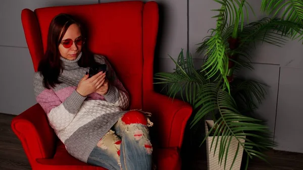 Woman Stylish Sunglasses Sitting Armchair Smartphone Serious Young Female Dark — Foto Stock