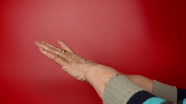 Пожилые женщины руки на красном фоне. Неузнаваемая зрелая женщина, показывающая свои руки. — стоковое видео