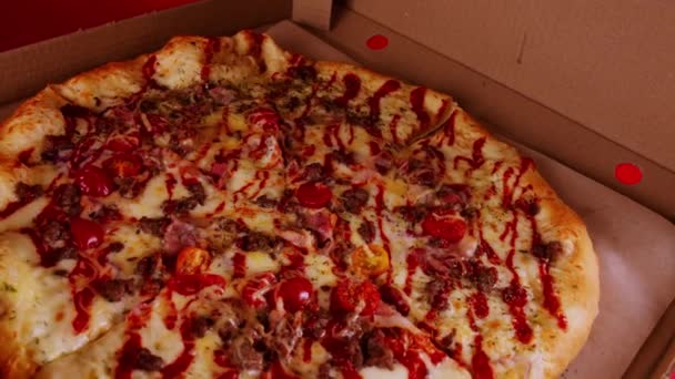 Apetyczna duża pizza w pudełku. Pyszna pizza z różnymi składnikami przędzenia. Zamknij drzwi. Pojęcie fast food i jedzenie na wynos. — Wideo stockowe