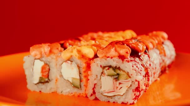 Apetyczne bułki sushi z sosem na żółtym talerzu. Smaczne bułki sushi z różnymi składnikami przędzenia na czerwonym tle. Zamknij drzwi. Pojęcie fast food i jedzenie na wynos. — Wideo stockowe