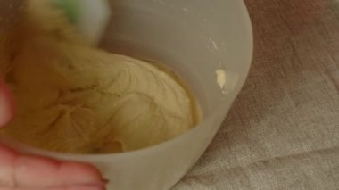 Masada krem şanti var. Mutfak spatulasıyla krema karıştıran tanınmamış biri. Kapatın. Muhallebi hazırlama kavramı.