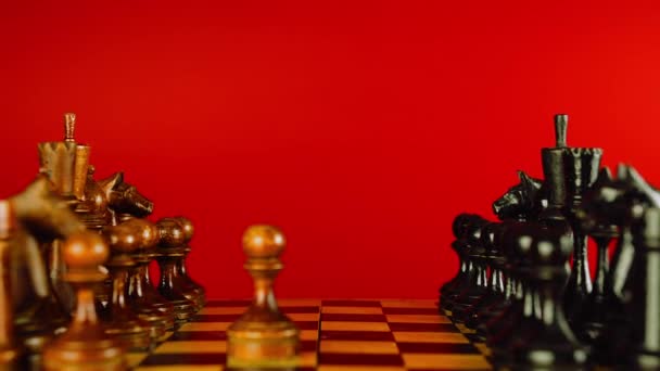 Крупним планом чорні шахові фігури на борту. Два ряди дерев'яних фігур на шахівниці на червоному тлі. Концепція розумної, логічної та стратегічної гри . — стокове відео
