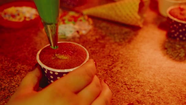 Kis süti az asztalon. Felismerhetetlen nő zöld krémmel díszíti a muffint. Közelkép a nők kezét díszítő torta puding. — Stock videók