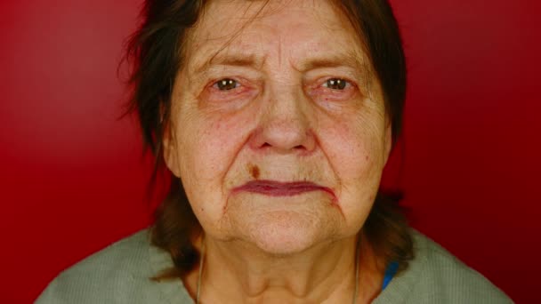 Зрелая женщина на красном фоне. Портрет бабушки, смотрящей вокруг и улыбающейся. — стоковое видео
