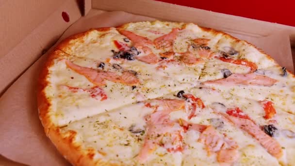 Apetyczna duża pizza w pudełku. Pyszna pizza z różnymi składnikami przędzenia. Zamknij drzwi. Pojęcie fast food i jedzenie na wynos. — Wideo stockowe