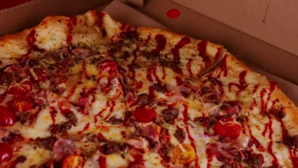大きなピザを箱に入れて食欲をそそる。異なる成分が回転するおいしいピザ。閉めろ。ファーストフードの概念と持ち帰り. — ストック動画