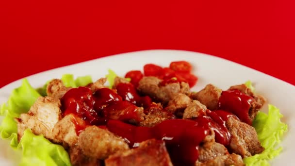 Pedaços suculentos de carne em molho em alface em prato branco. Aperitivo porção temperada de carne em ketchup girando em fundo vermelho. Fechar. — Vídeo de Stock