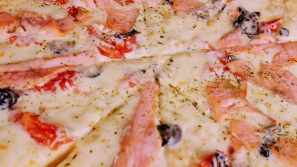 Textura de apetitosa pizza grande. Deliciosa pizza con diferentes ingredientes girando. De cerca. Concepto de comida rápida y comida para llevar. — Vídeo de stock