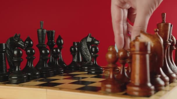 Close up de peças de xadrez de madeira branca e preta a bordo. Mão das mulheres faz movimento de peão branco no tabuleiro de xadrez. Conceito de jogo inteligente, lógico e estratégico. — Vídeo de Stock