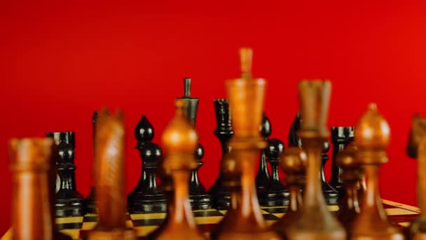 Fekete sakkfigurák közelsége a fedélzeten. Két sor fa figura a sakktáblán vörös alapon. Az intelligens, logikus és stratégiai játék fogalma. — Stock videók