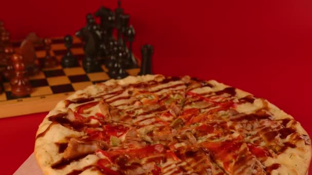 İştah açıcı küçük pizza dönüşü. Farklı malzemeli lezzetli pizza ve kırmızı zemin üzerinde ahşap satranç taşları olan sos. Fast food ve atıştırmalık yemek kavramı. — Stok video