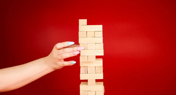 Jogo Jenga Fundo Vermelho Mão Mulher Tira Pequenos Blocos Madeira — Fotografia de Stock