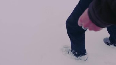 Tanınmayan biri kışın kar yığınlarında yürür. Yürürken insanın ayakları karlara düşer.