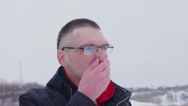 Man he runs his hand over his nose and sniffles standing outside in cold weather in winter. Concept: symptoms colds or Coronavirus Omicron — Stock Video