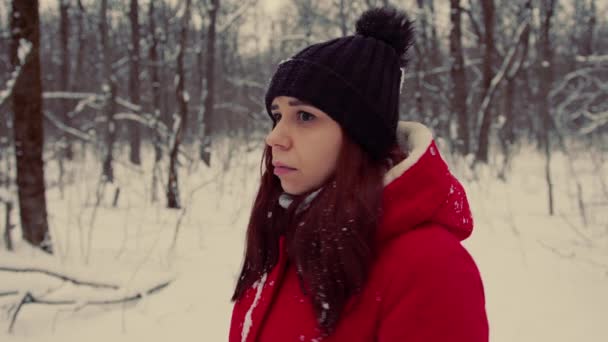 Una donna si è persa nella foresta in inverno, si guarda intorno alla ricerca di un modo. Femmina in una calda giacca rossa è spaventata da sola nella foresta. — Video Stock