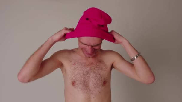 Naken man sätter på rosa balaklava. Hemlig kille tar på sig mask, döljer ansiktet. — Stockvideo