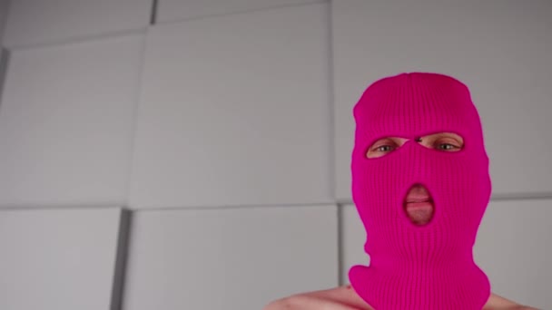 Retrato de un hombre irreconocible en pasamontañas rosa. Hooligan en máscara mirando a la cámara. — Vídeo de stock