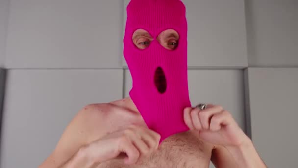 Alaston mies laittaa vaaleanpunaista balaclavaa. Salainen kaveri laittaa naamio, piilossa kasvot. — kuvapankkivideo