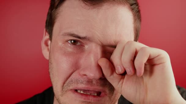 Porträtt av en gråtande man med röd bakgrund. En orakad man gråter och sörjer — Stockvideo