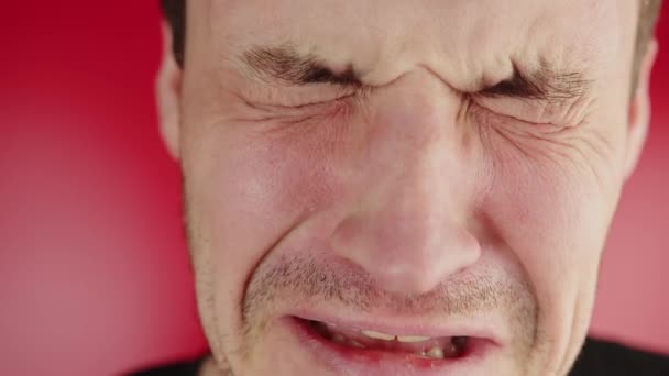 Retrato de un hombre llorando sobre un fondo rojo. Un hombre sin afeitar está llorando y afligido — Vídeo de stock