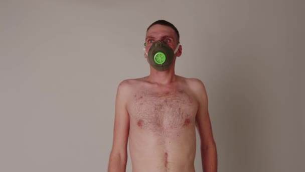 Hombre desnudo en respirador de pie cerca de la pared. Varón con el torso desnudo en máscara protectora mirando hacia otro lado. Concepto de prevención de la infección viral. — Vídeos de Stock