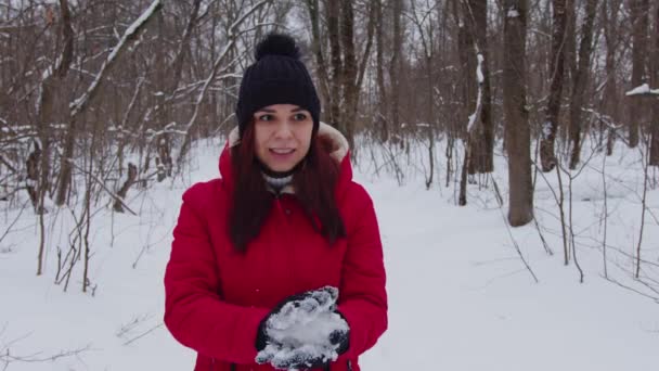 Mujer joven en sombrero y guantes esculpe bola de nieve, de pie en el bosque. hembra juguetona en ropa de abrigo se regocija nieve blanca en temporada de invierno. — Vídeo de stock