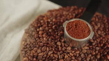 Kahve çekirdekleri ile ahşap tahtanın üzerinde portafilter içinde öğütülmüş kahve ve buhar. Süzgeç kabuğunda taze öğütülmüş kahve ve mis kokulu içecek hazırlamak için kavrulmuş fasulye..