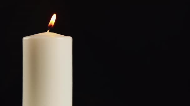 Una vela blanca ardiente sobre un fondo negro o en la oscuridad. Concepto: Símbolo del Dolor y Día Mundial del Cáncer — Vídeos de Stock