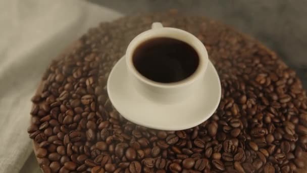一杯咖啡和茶托在咖啡豆上 用散热的蒸汽 用烤豆和烟熏过的新鲜咖啡的成分 配制香醇的概念 — 图库视频影像