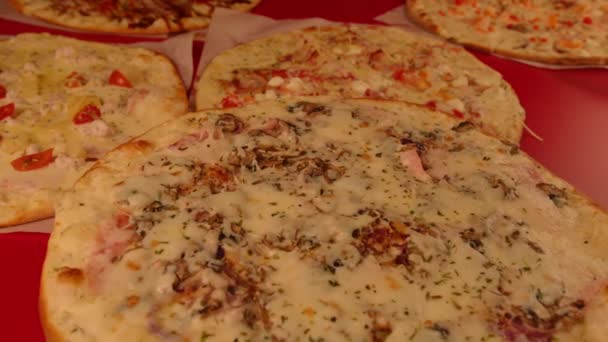 Apetyczna mała pizza wirująca na tle innych pizzy. Pyszna pizza z różnymi składnikami. Koncepcja imprezy, fast food i jedzenie na wynos. — Wideo stockowe