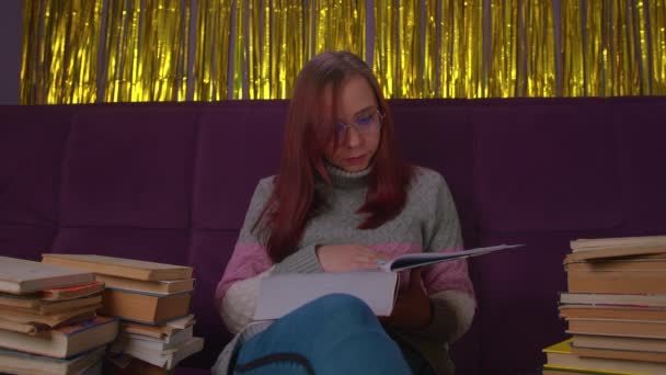 책읽는 데지친 여대생. 책 과 책을 쌓아 놓고 소파에 앉아 있는 관대 한 젊은 여성 — 비디오