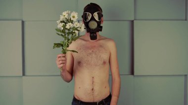 Gaz maskeli, çiçekli, yüzsüz bir adam. Siyah gaz maskeli çıplak bir gövde ve bir buket taze beyaz çiçekle tanınmayan bir adam. Konsept: alerji ve çevre kirliliği