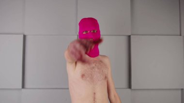 Çıplak vücutlu, pembe kar maskeli tanınmayan biri ellerden hayali bir silah yapar ve hayali bir atış yapar. Zorba erkek kameraya nişan alır ve ateş eder..