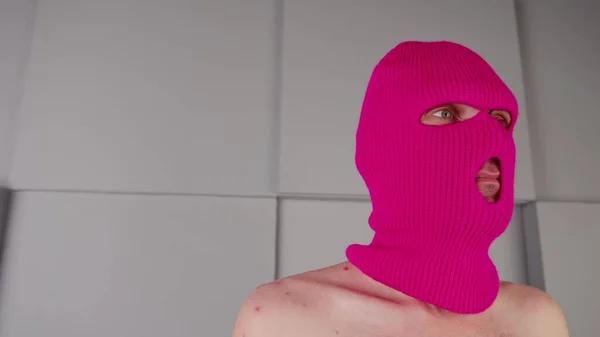 Egy felismerhetetlen férfi arcképe rózsaszín maszkban. A maszkos huligán félrenéz.. — Stock Fotó