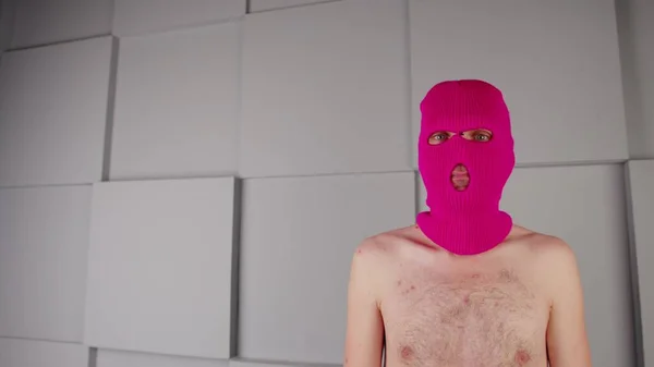 Egy felismerhetetlen férfi arcképe rózsaszín maszkban. A maszkos huligán a kamerába néz.. — Stock Fotó