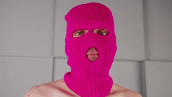 Egy felismerhetetlen férfi arcképe rózsaszín maszkban. A maszkos huligán a kamerába néz.. — Stock Fotó