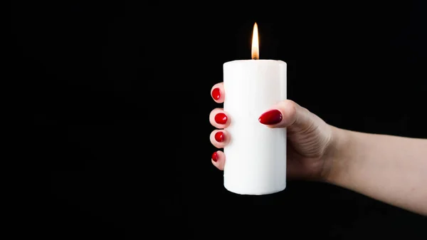 Mujer de las cosechas con vela encendida en el estudio. Cultivo hembra con clavos rojos sosteniendo vela ardiente en las manos sobre fondo negro —  Fotos de Stock