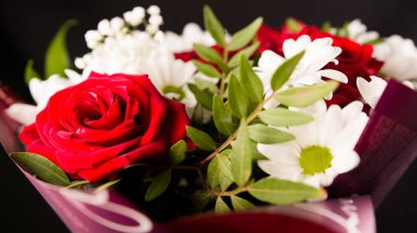 Yakın plan kırmızı güller ve papatyalar.