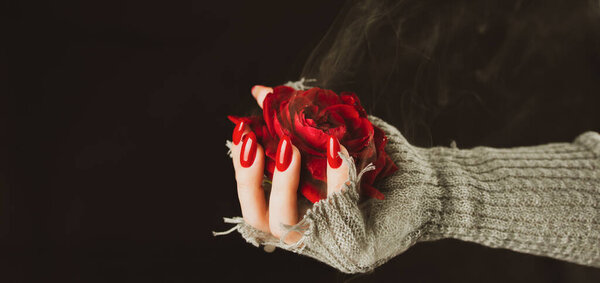 Женщина в свитере с красной розой на черном фоне. Сверху красная роза в руке на черном фоне.