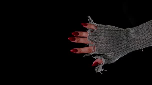 女人的手在黑色的背景上有红色的指甲。戴着时髦针织手套的无法辨认的女人,露出了修指甲的样子.护理与美的概念. — 图库视频影像