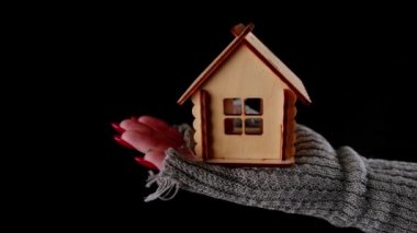 Siyah arka planda tahta oyuncak evi olan bir çiftçi. Siyah arka planda küçük ahşap bir oyuncak evi tutan isimsiz şahsın en iyi görüntüsü.