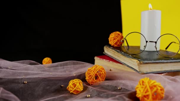 Eyeglasses on old books. Glasses on stack of books on black and yellow background surrounded by decor. — Stock Video