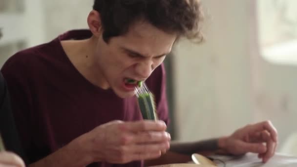 A young man is sitting at a table and eating a cactus. Concept: Crazy challenge — Stock Video