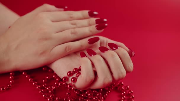 Desde arriba de la cosecha mujer anónima con cuentas rojas y con manicura roja sobre fondo rojo en el estudio — Vídeos de Stock